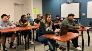 Students sitting at desks in classroom smiling